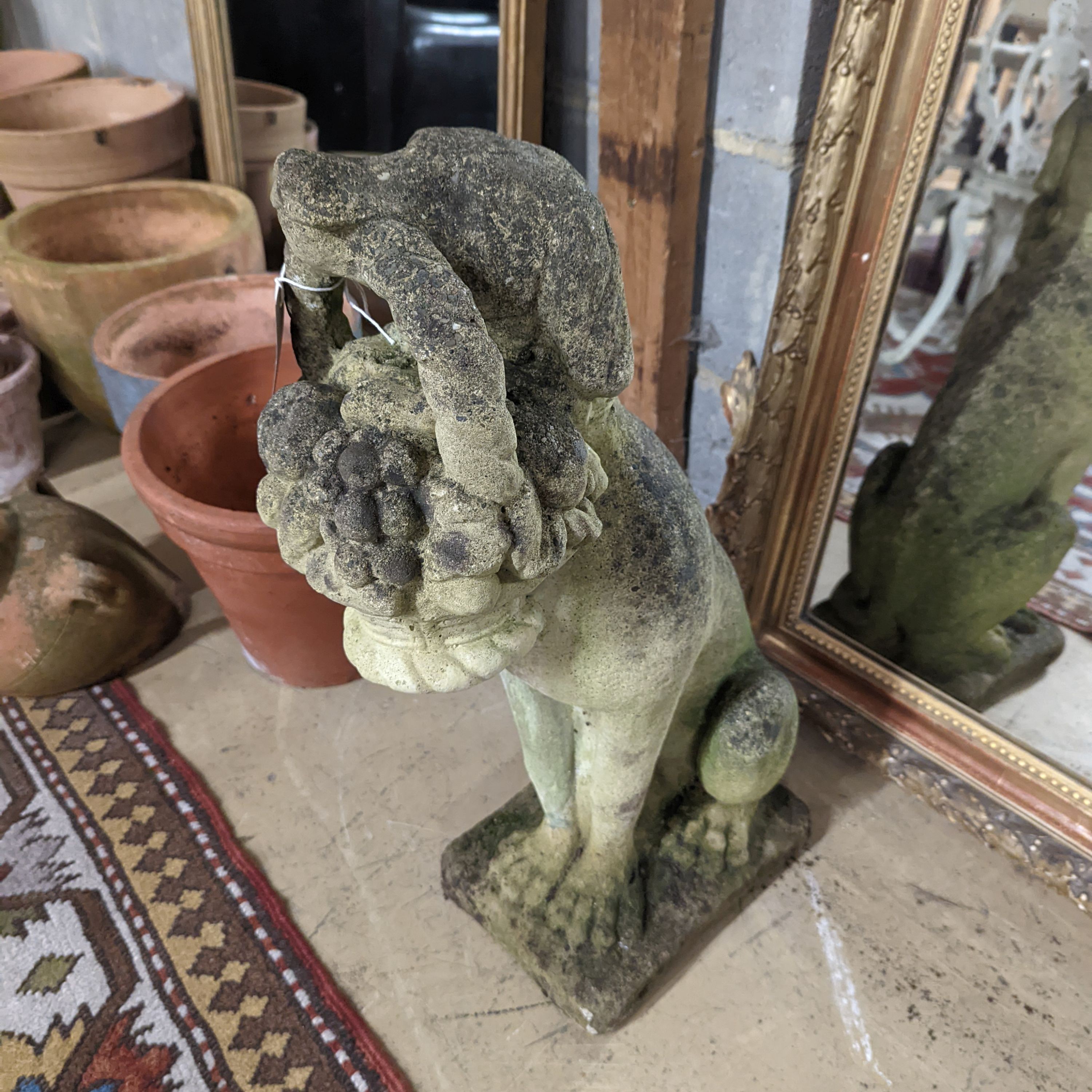 A reconstituted stone garden ornament of a seated hound, a basket of fruit in its mouth, height 60cm